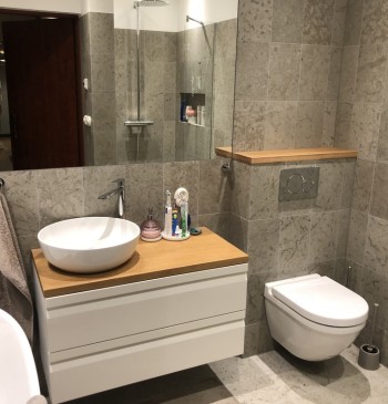 Badrum med badkar och dusch med samma sten på golv och väggar